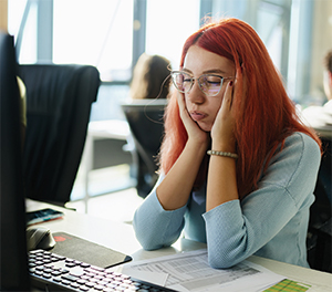 Woman sitting at desk with head in hands